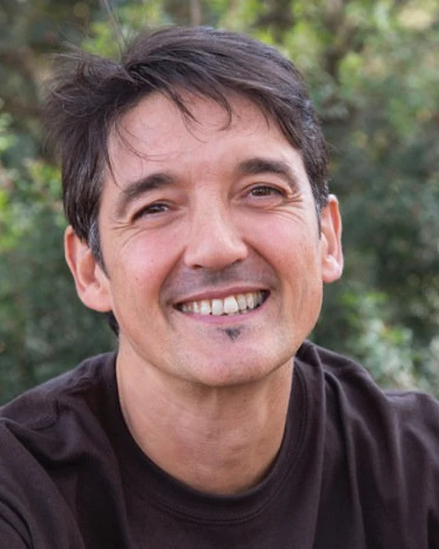 Manu Villaescusa sonriendo, con jersey oscuro y plantas detrás
